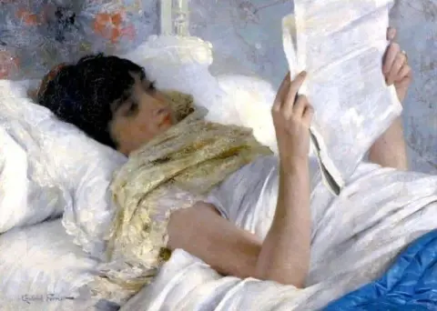 ベッドで新聞を読む女性