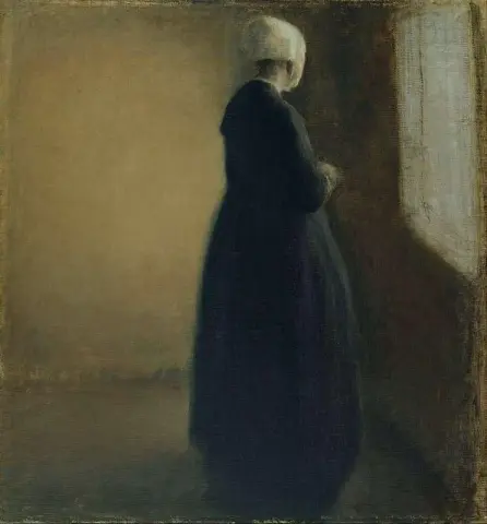 En gammal kvinna som står vid ett fönster 1885